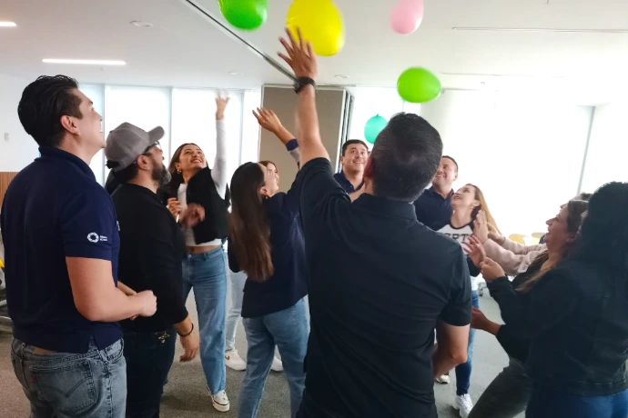 Fotografía de la actividad grupal de compañeros de trabajo realizando team building jugando con globos
