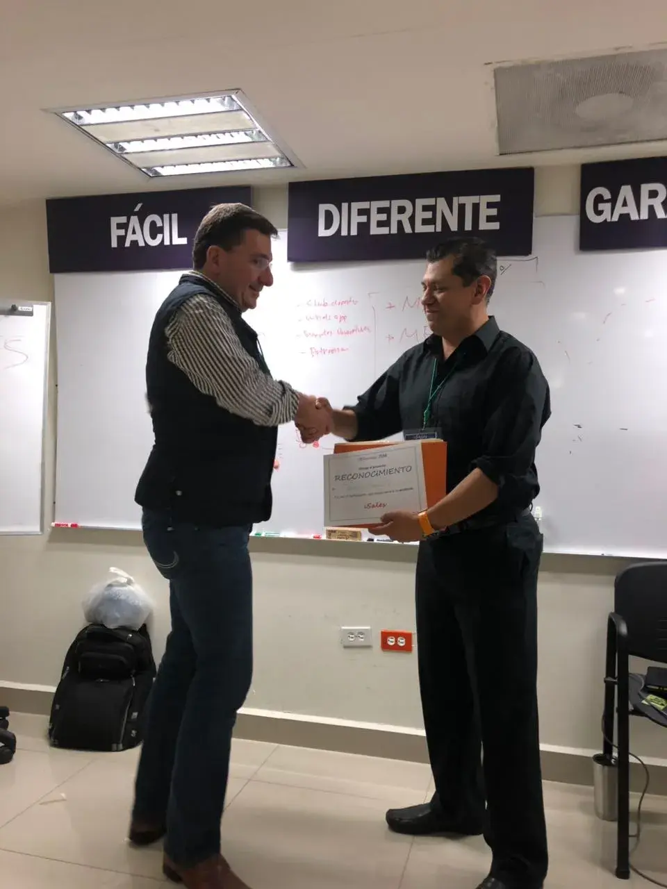 Dos hombres estrechando su mano durante un entrenamiento de coaching empresarial Dos hombres se estrechan la mano durante una dinámica de integración en un entrenamiento de coaching empresarial enfocado en fortalecer relaciones profesionales.