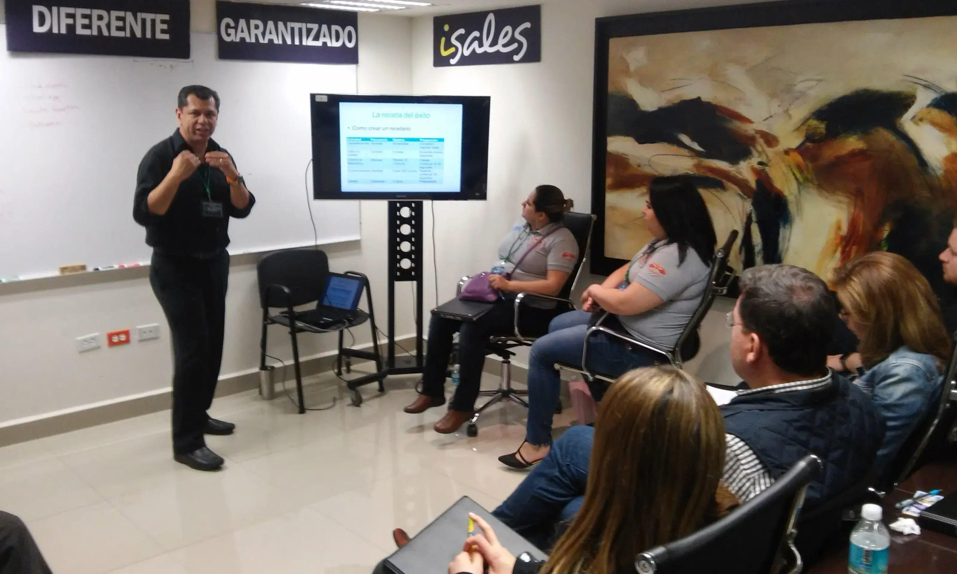 Hombre exponiendo frente a un grupo de personas sentadas Hombre exponiendo ideas frente a un grupo de personas sentadas en sala de capacitación como parte de un programa de formación en coaching empresarial estratégico.