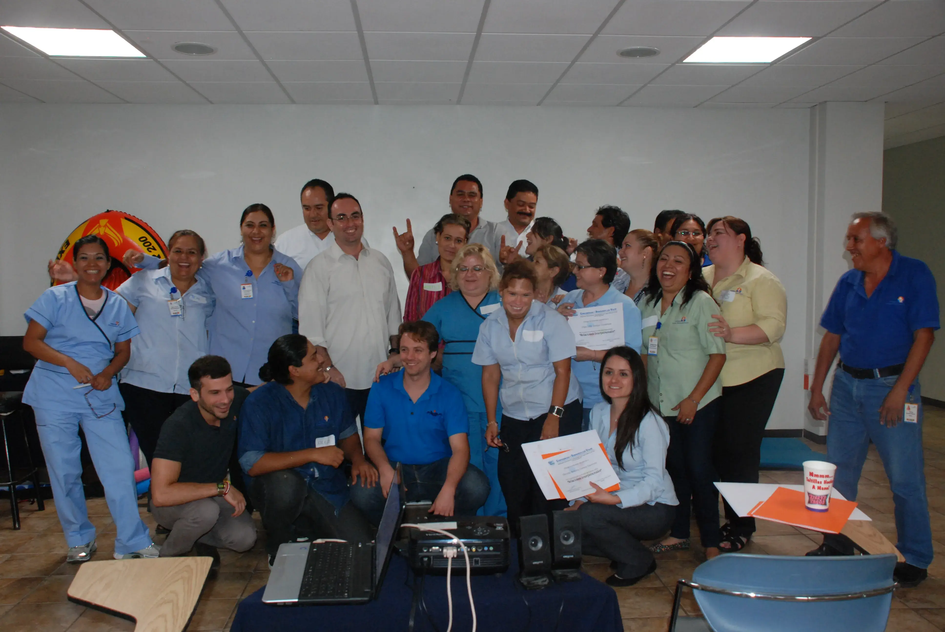 Foto de grupo de colaboradores con certificado en taller de comunicación empresarial Grupo de colaboradores posa con certificado al finalizar un taller de comunicación empresarial, destacando el trabajo en equipo y el desarrollo organizacional.