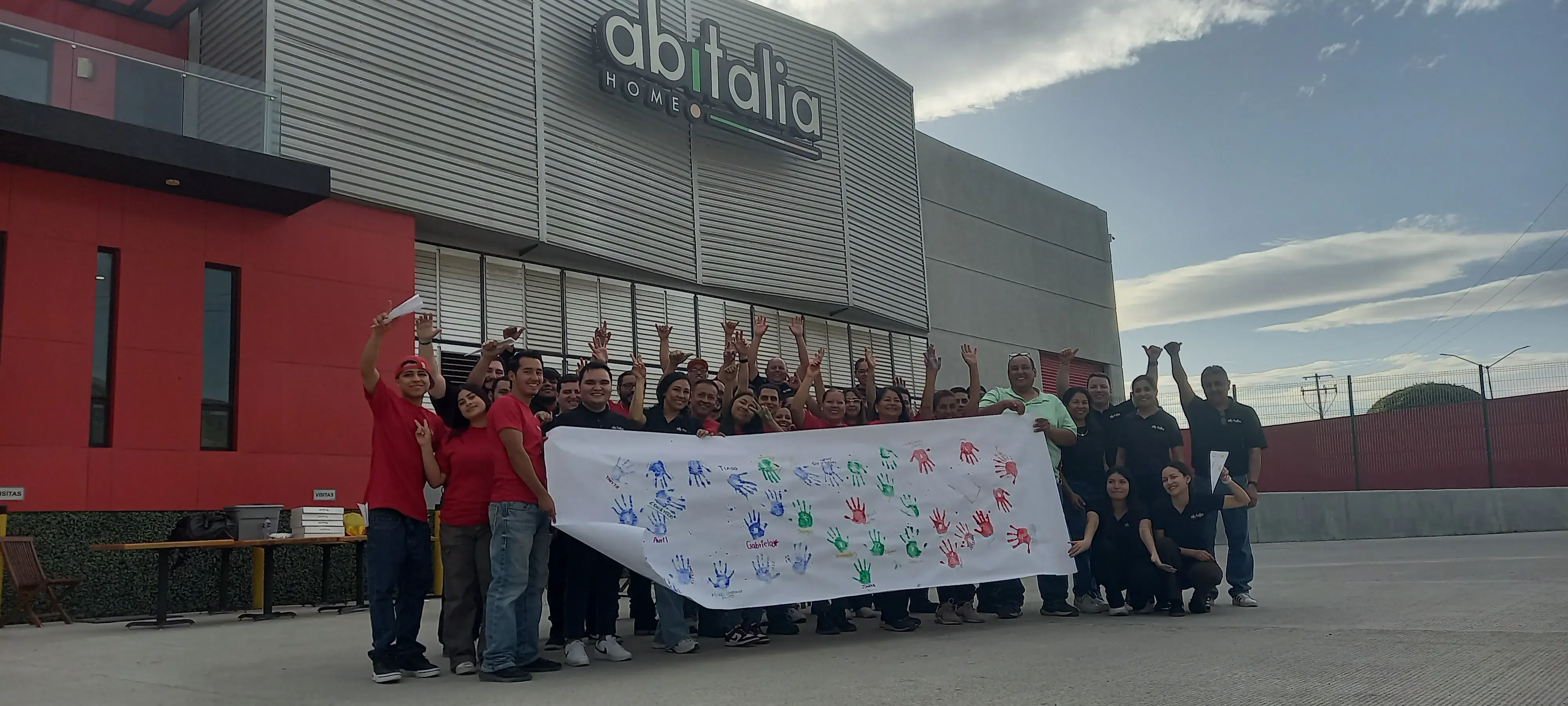 Equipo sosteniendo una pancarta para dar inicio a su capacitación en liderazgo y ventas con inteligencia emocional para potenciar su forma de trabajar