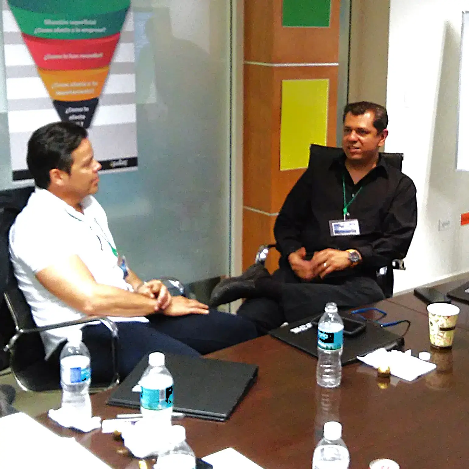 Dos hombres conversando sobre el curso de ventas de Econvalor Fotografía de Dos hombres sentados conversando sobre el curso de ventas de Econvalor en una oficina