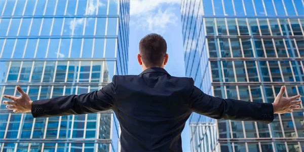 Hombre abriendo los brazos ante oficinas donde se abren posibilidades de liderazgo efectivo gracias a Econvalor